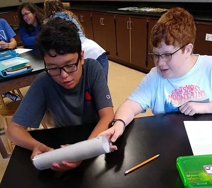 Students studying a mosquito sample in a tube.