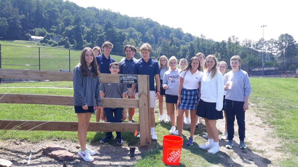 Students in the field standing beside a fence