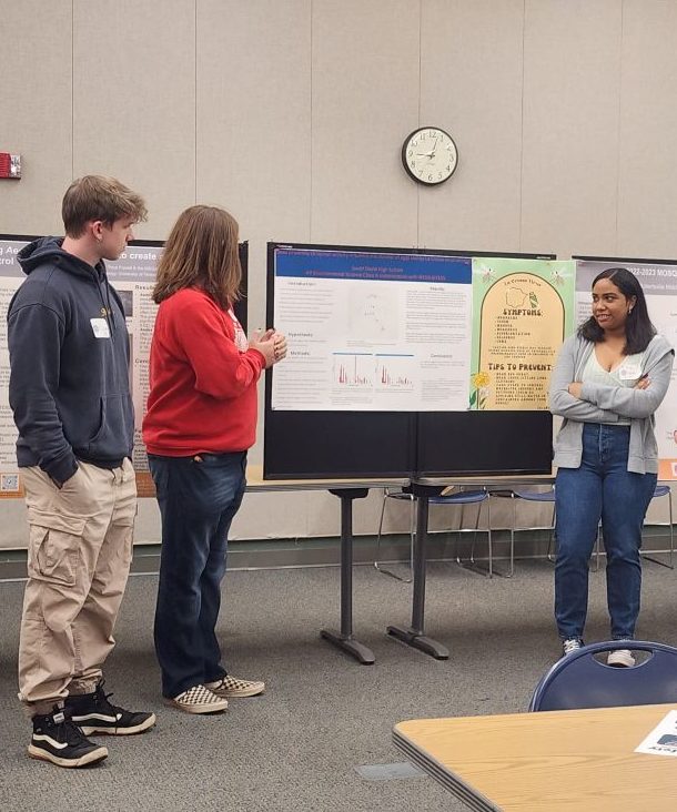 Students having a discussion around a poster presentation session. 
